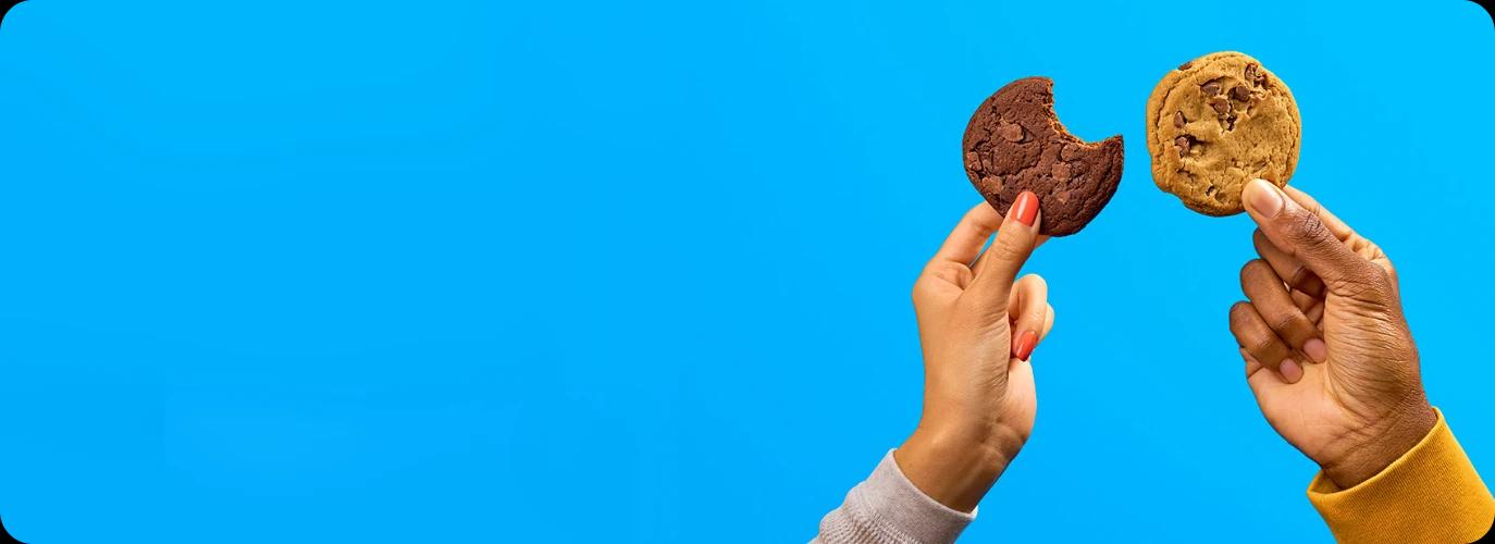 Chocolate chip cookies held against a blue background