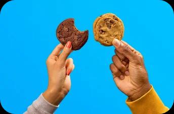 Chocolate chip cookies held against a blue background.